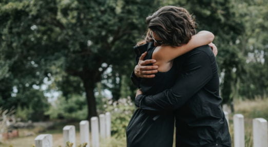 two people hugging at a funeral