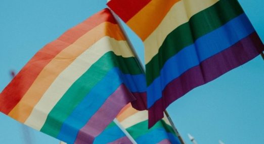 lgbtq rainbow flags in front of blue sky