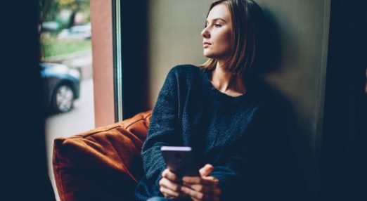 woman on her phone looking thoughtful